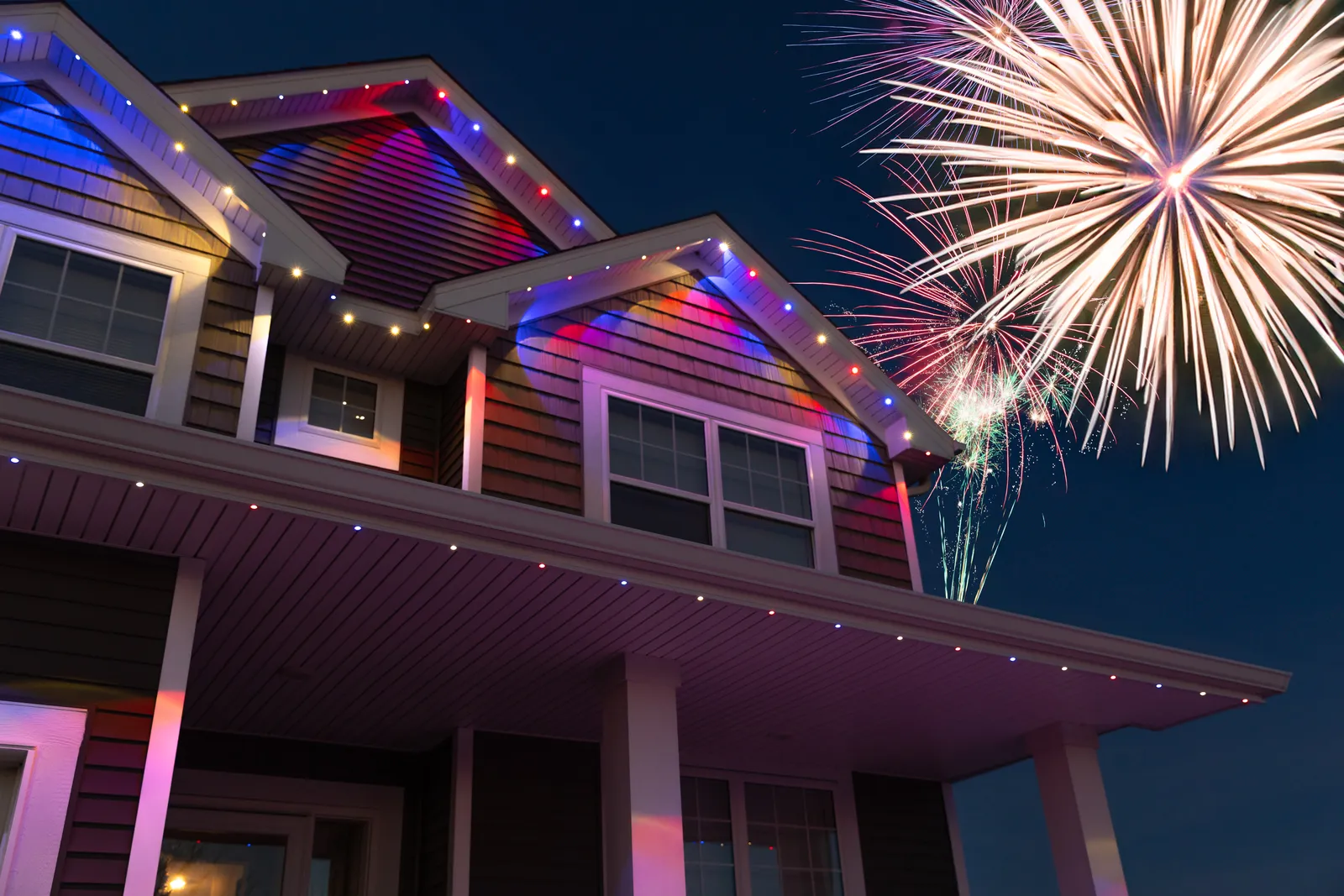 Home outlined in colour-changing permanent lighting with fireworks overhead