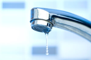 Drop of water falling from a silver sink faucet