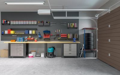 Garage workspace with table, tools along wall, and concrete floor.