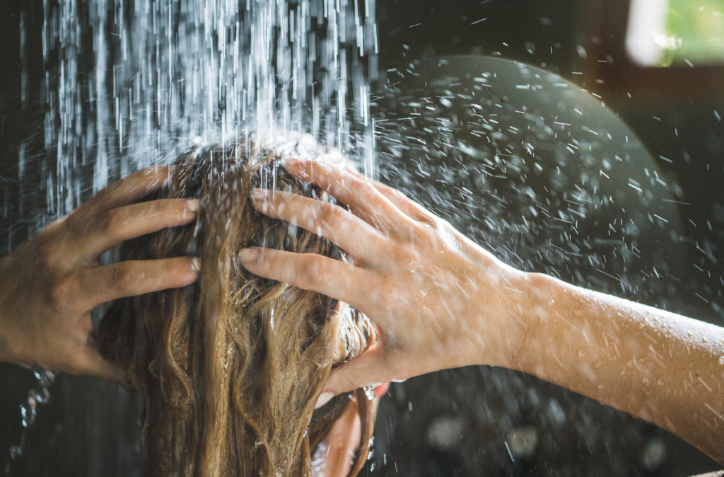 Close up of a woman washing her hair while showering in the morning.
