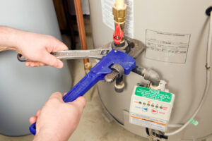 Dean's plumber working on a water heater, tightening connections
