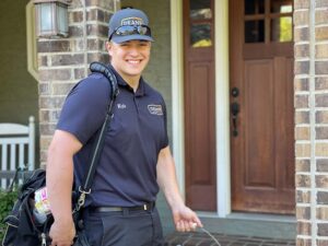 Smiling technician named Kyle from Dean's Home Services standing in front of a home's front door