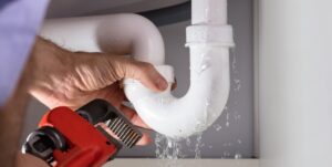 Close-up Of Plumber Fixing White Sink Pipe With Adjustable Wrench